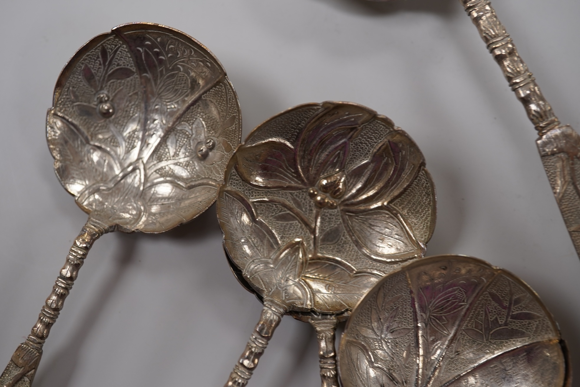 A set of twelve early 20th century Chinese Export white metal small spoons, maker LS, decorated with foliage and character mark, 10cm, a set of ten similar larger spoons, same maker, 12.3cm and another set a six similar